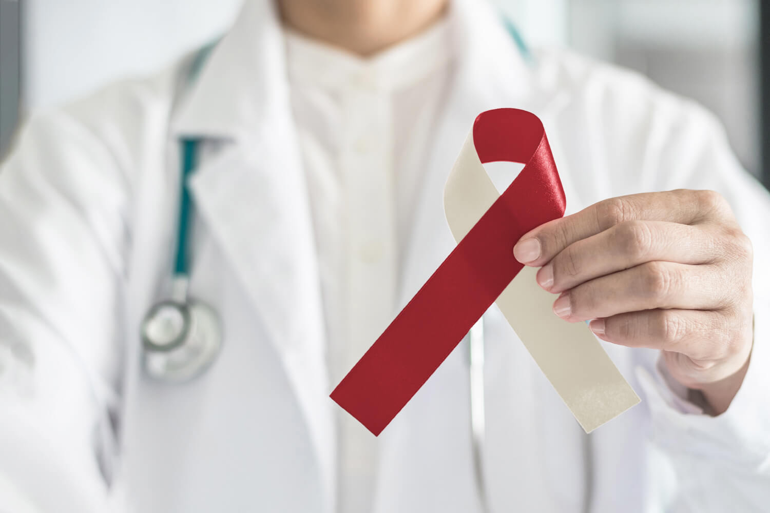 Dentist holds up a red and cream ribbon for oral cancer awareness in Fayetteville, AR