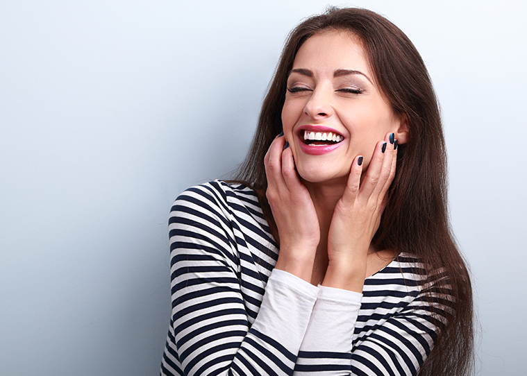 woman smiling while holding her face