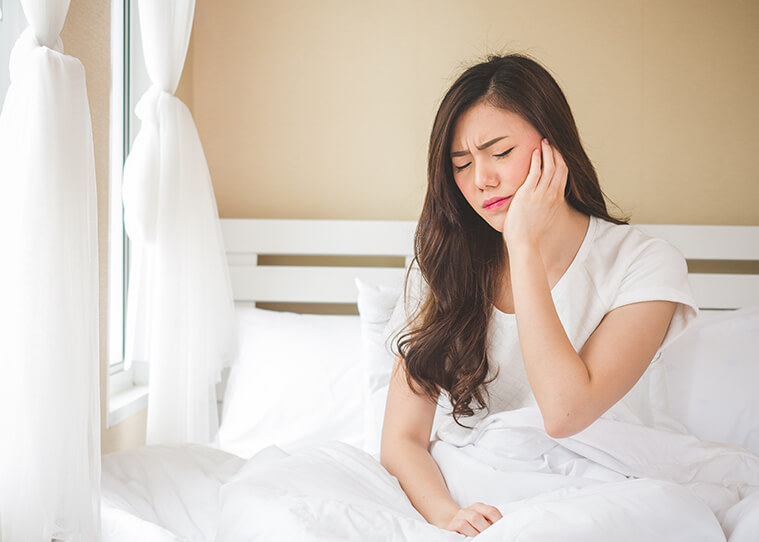 woman holding her jaw in pain