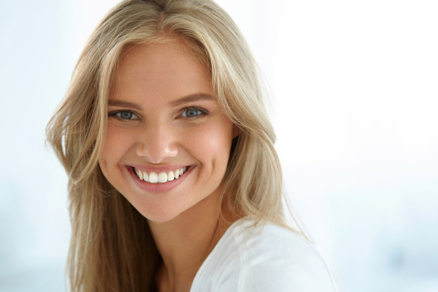 young blond woman smiles showing off her teeth whitening treatments