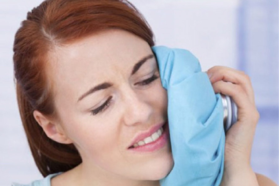 woman holds an icepack to her jaw after wisdom teeth extractions