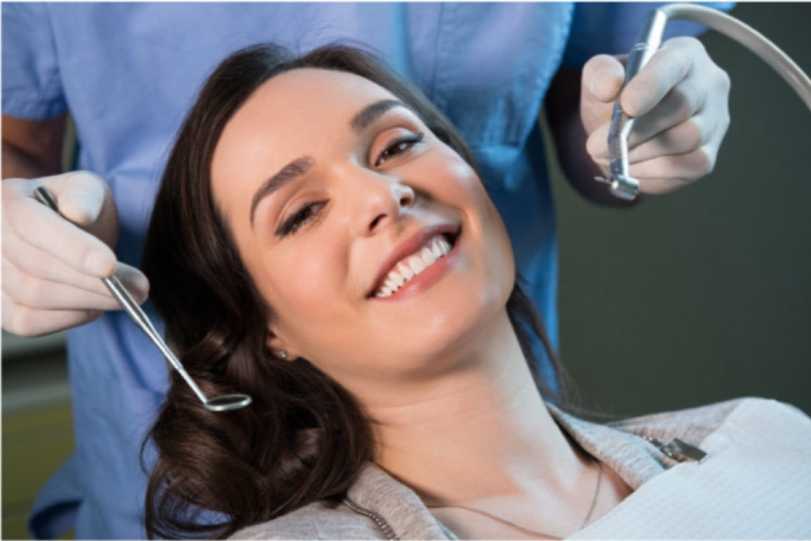 young woman in the dentist chair smiles after getting veneers