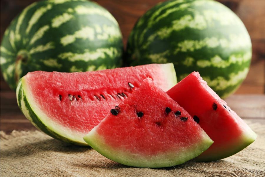 three watermelon with one sliced up for eating